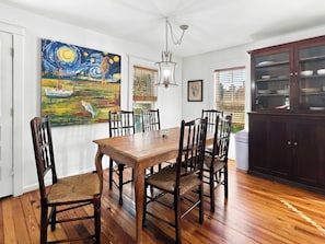 A dining area with a wooden table and chairs, a chandelier, and artwork on the walls. - Historic Two Bedroom Apartment Overlooking Olde Towne Daphne (Daphne)