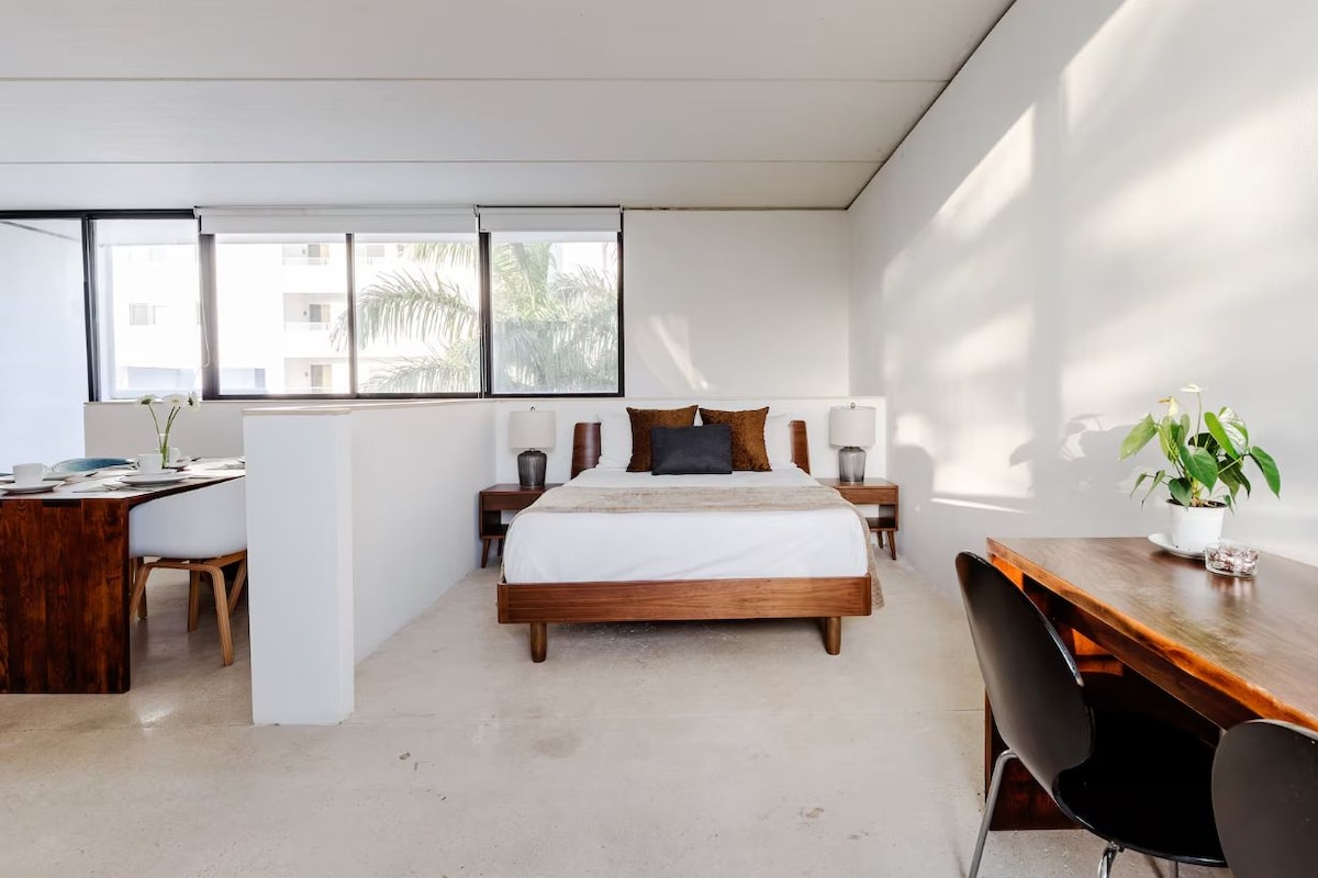 A modern bedroom with a wooden bed, bedside tables, a desk, and a chair.
