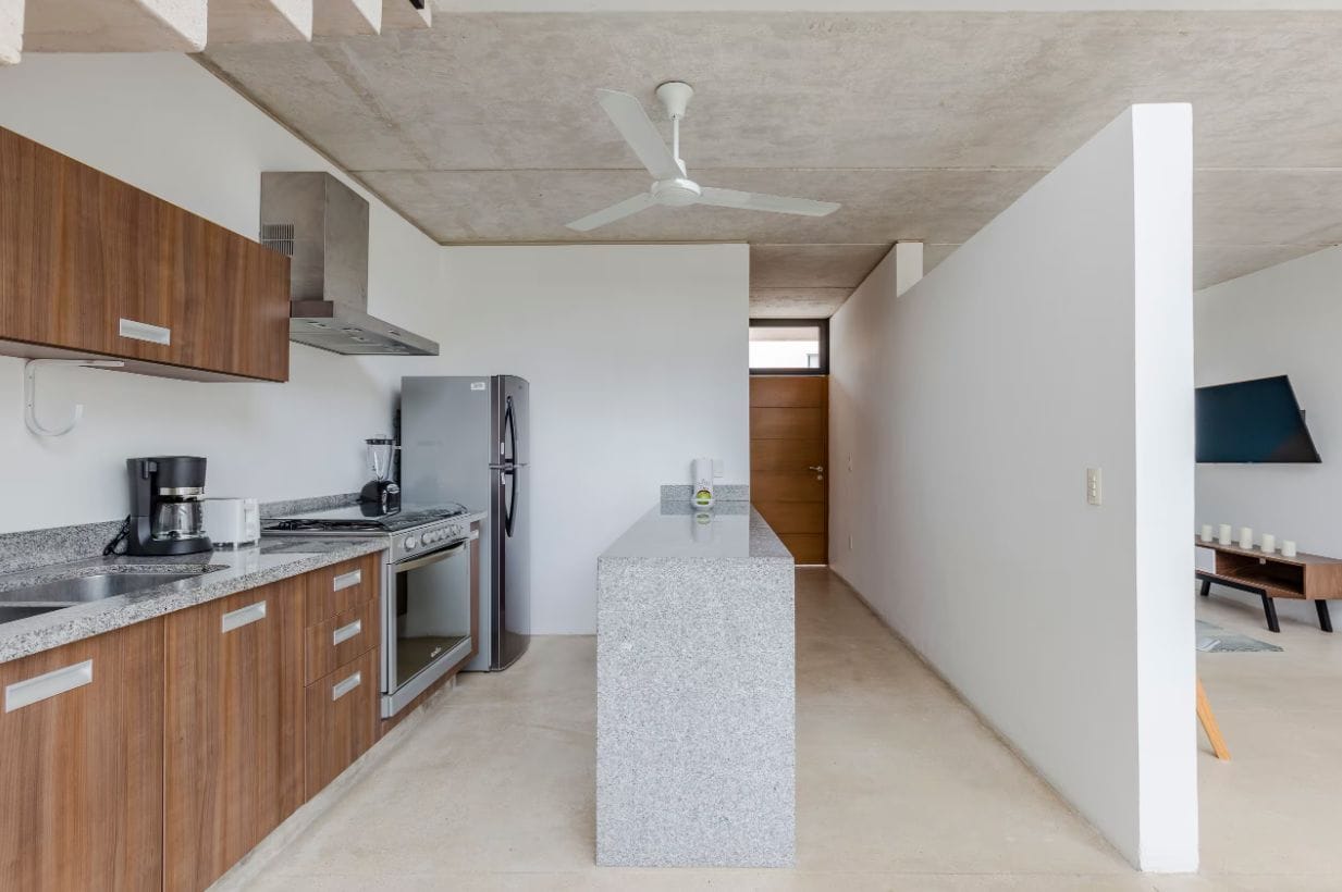 Una cocina moderna con encimeras de granito, electrodomésticos de acero inoxidable y armarios de madera.