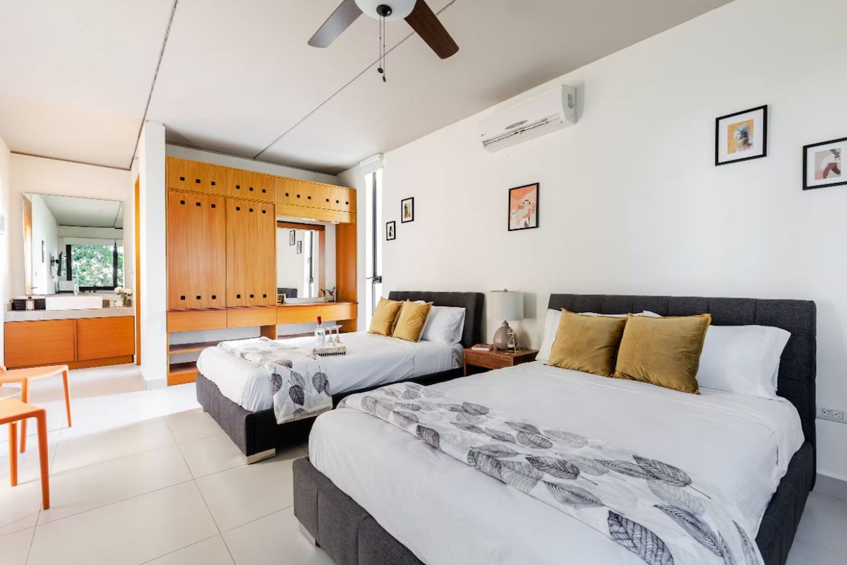 A hotel room with two beds, a kitchenette, and a dining area.
