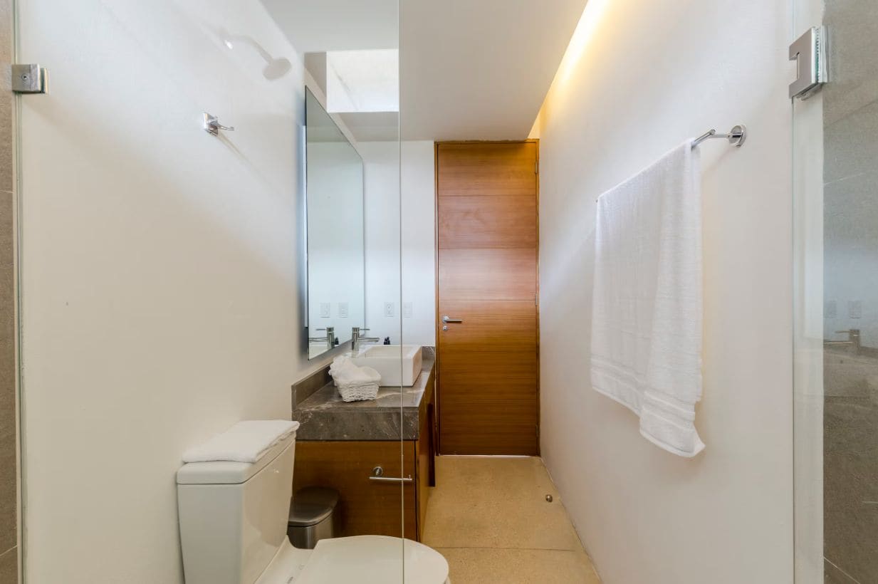 A compact bathroom with a toilet, sink, and mirror.