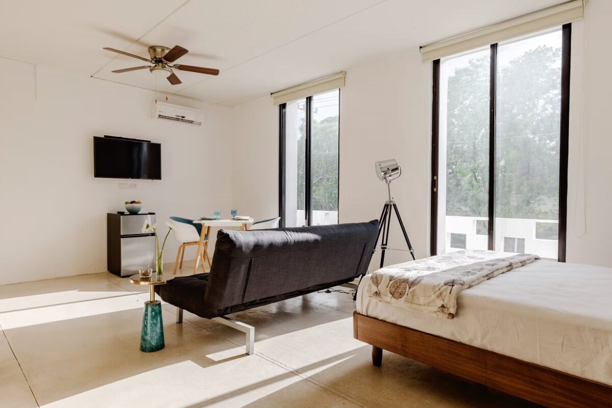 A modern bedroom with a bed, a desk, a chair, and a ceiling fan.