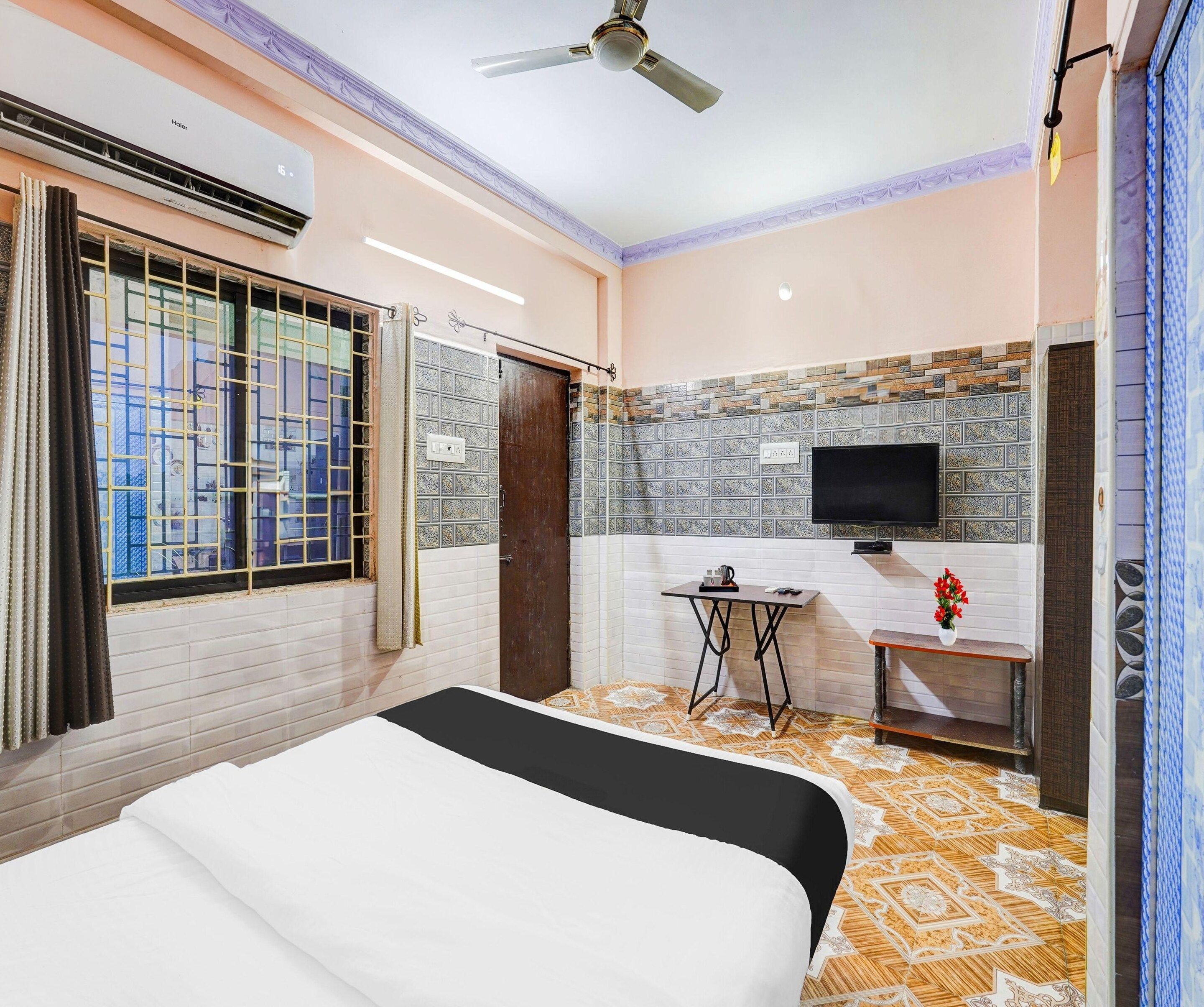 A hotel room with a bed, a TV, a small table, and a ceiling fan.