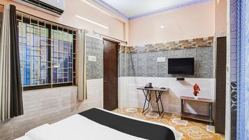 A hotel room with a bed, a TV, a small table, and a ceiling fan.