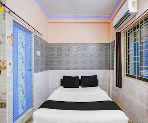Quarto com cama, janela com cortina e parede com azulejos estampados.