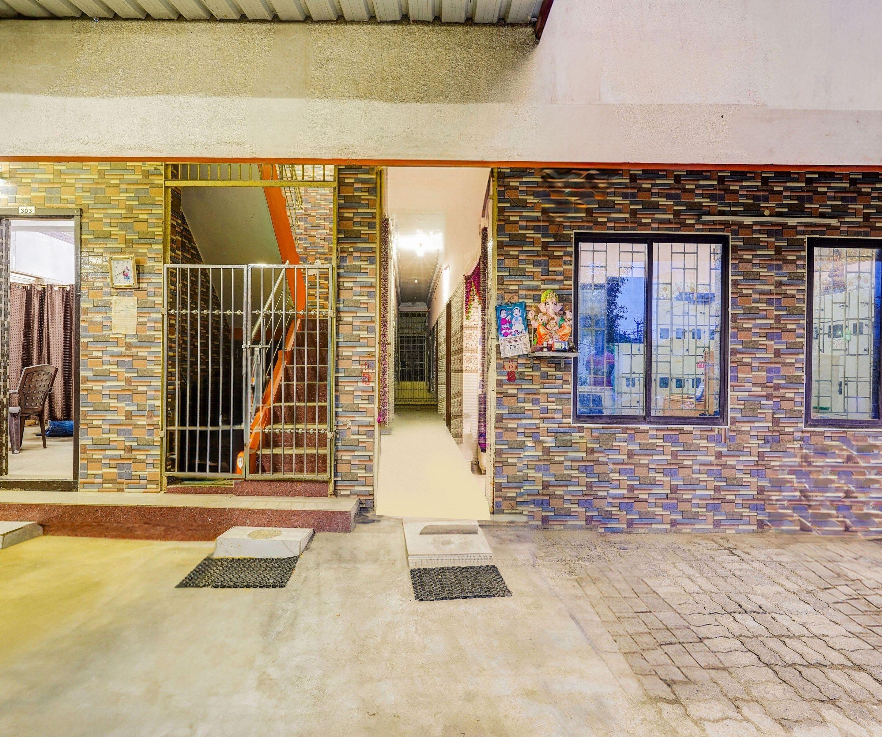 A building entrance with a tiled facade, a metal gate, and a staircase leading inside.