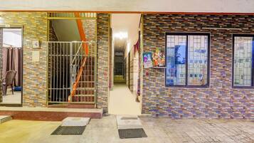 A building entrance with a tiled facade, a metal gate, and a staircase leading inside.