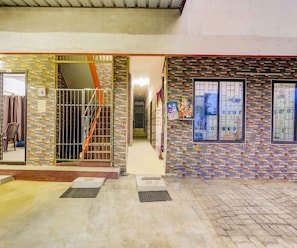 Entrada de un edificio con fachada de azulejos, un portón de metal y una escalera que da acceso al interior.