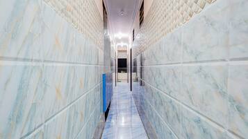 A hallway with marble walls and a shiny floor, leading to a door at the end.