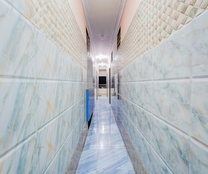 A hallway with marble walls and a shiny floor, leading to a door at the end.