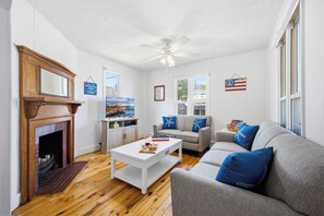 A living room with a fireplace, a ceiling fan, a television, a sofa, and a coffee table. - Perfect Family Beach Getaway (Old Orchard Beach)