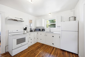 A modern kitchen with white cabinetry, a built-in oven, microwave, and refrigerator. - Perfect Family Beach Getaway (Old Orchard Beach)