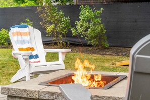 A backyard with a fire pit and a white chair with a striped towel. - Perfect Family Beach Getaway (Old Orchard Beach)