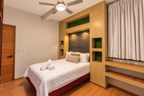Ein modernes Schlafzimmer mit einem Bett, einem Deckenventilator, einer eingebauten Regalanlage mit Grünpflanzen und einem Fenster mit Vorhängen.