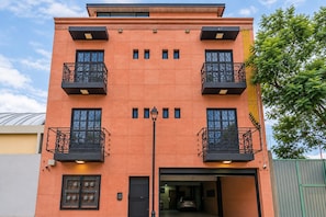 Ein mehrgeschossiges Gebäude mit Balkonen, einer Garage und einer Straßenlaterne.