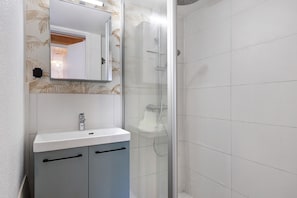 A bathroom with a shower, a sink, and a mirror.