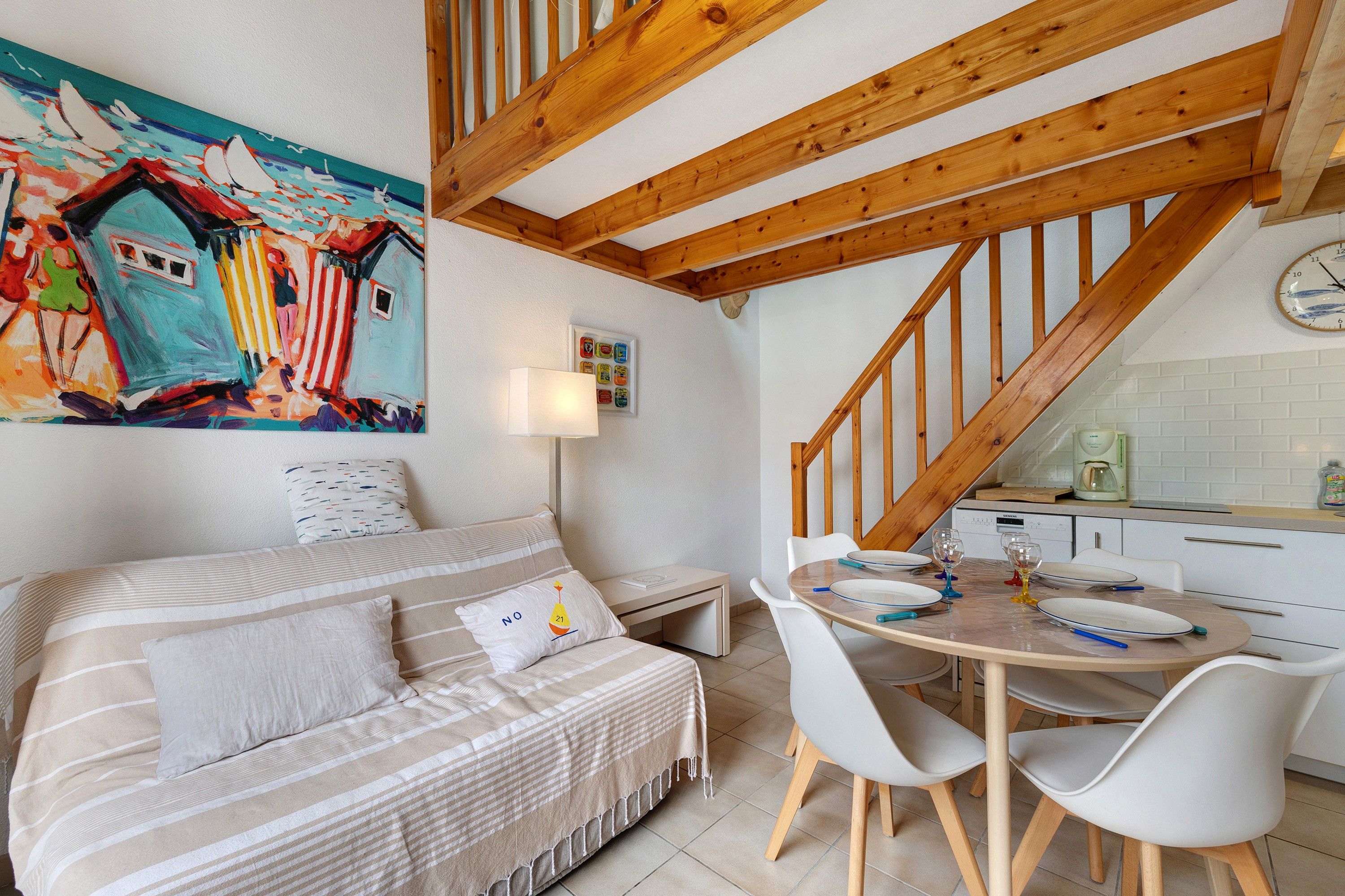 Ein gemütliches Schlafzimmer mit einem Bett, einem Gemälde, einem Nachttisch und Blick auf eine Küche.