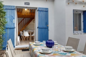 A dining area with a table set for two, a blue vase, and a window with a curtain.