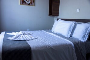 Una habitació d'hotel amb un llit ben fet, una presa elèctrica i un interruptor de llum fixat a la paret.