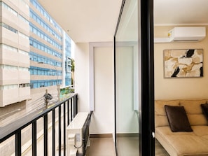 Un appartement moderne doté d’un balcon, d’un canapé et d’une grande fenêtre.