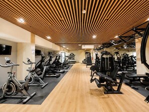 A gym with cardio machines, weightlifting equipment, and a wooden ceiling. - 2 dormitorios San Isidro AC y coworking (Lima)