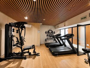 Une salle de sport équipée de matériel d’exercice, de tapis de course et d’un mur d’encouragement.