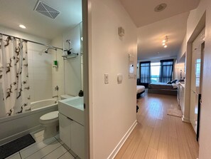 A modern hotel bathroom with a bathtub, toilet, and sink. - Cozy 3 Beds Suite (Toronto)