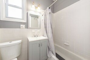 A bathroom with a toilet, sink, mirror, and shower. - Spacious 4BR Newark Stay,EWR, Seton Hall + NYC (Newark)