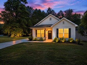 A single-story house with a front porch, a driveway, and a well-maintained lawn. - The Haven at Holly Springs (Holly Springs)