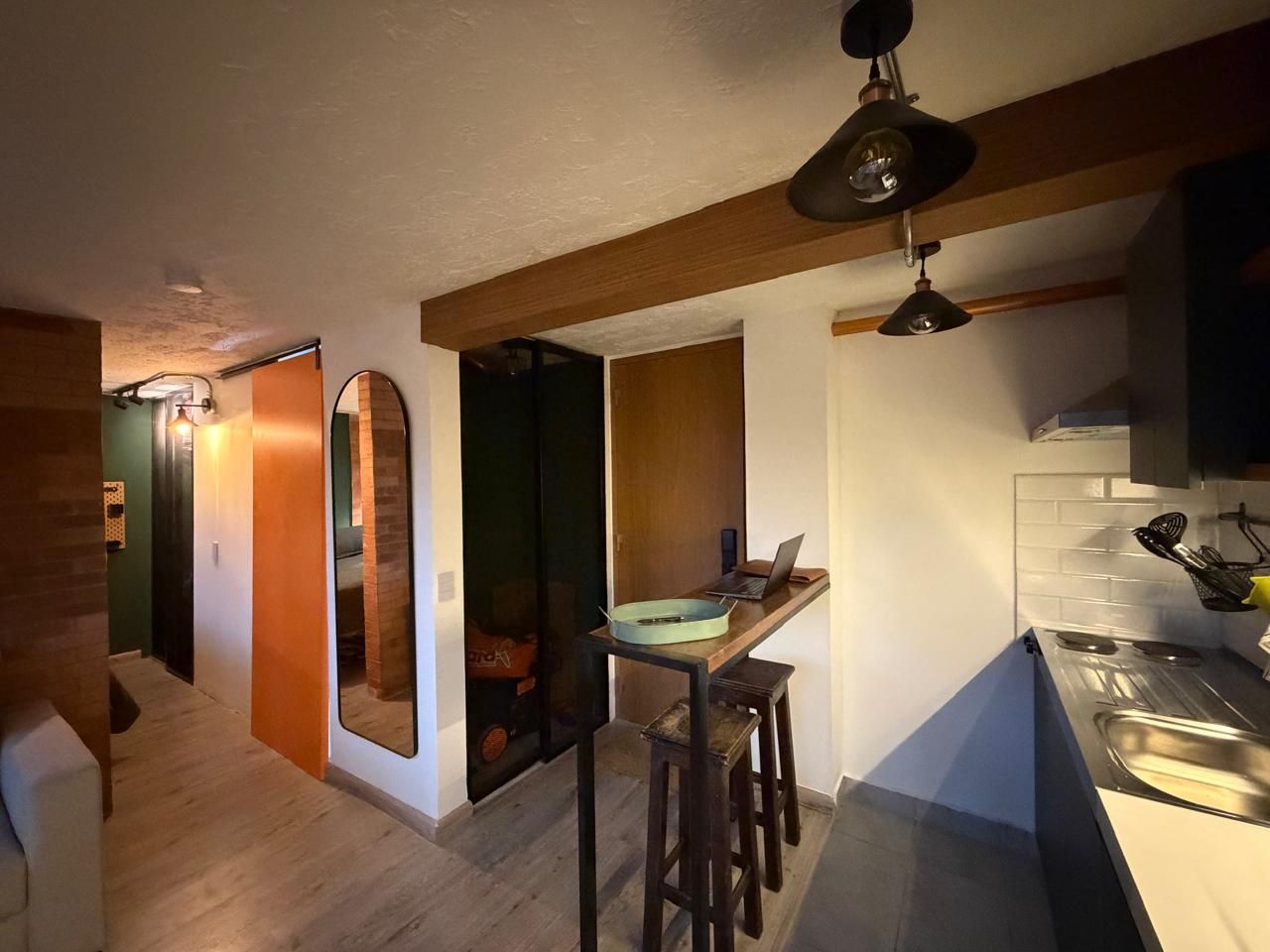 A compact kitchen with a wooden countertop, a laptop, and a sink.
