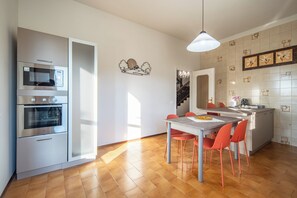 Una cocina moderna con electrodomésticos integrados, un comedor con mesa y sillas, y un elemento decorativo en la pared.
