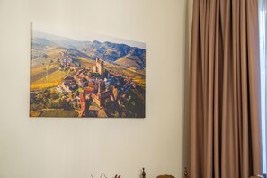 Un cuadro enmarco de un paisaje que muestra un pueblo con una torre destacada, colgado en una pared.