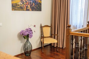 A room with a wooden chair, a vase with flowers, a painting on the wall, and a staircase with wooden railings. - Sinfonia di Langa - Three Bedroom Villa, Sleeps 6 (Alba)