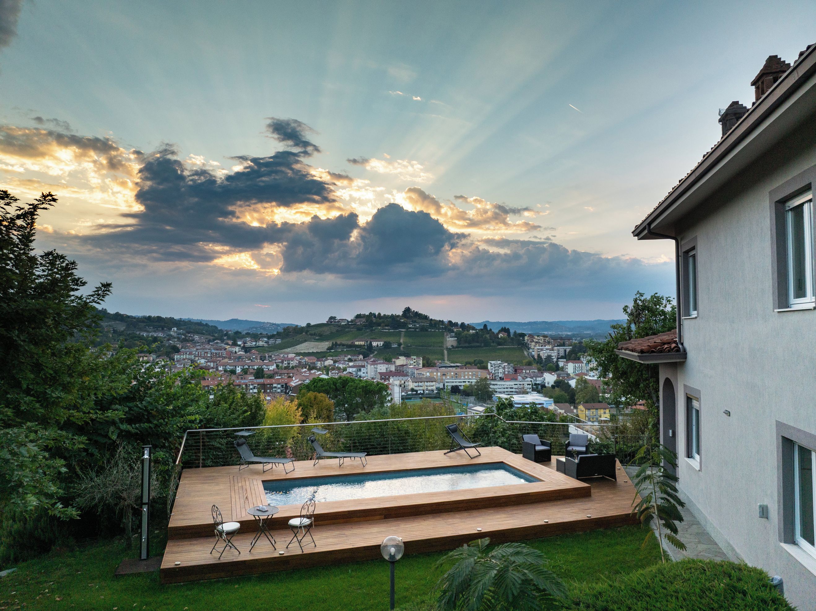 Una casa moderna con piscina, mobiliario exterior y vista a un pueblo.