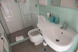 A bathroom with a toilet, bidet, sink, and shower. - Residenza Battistessa (Caserta)