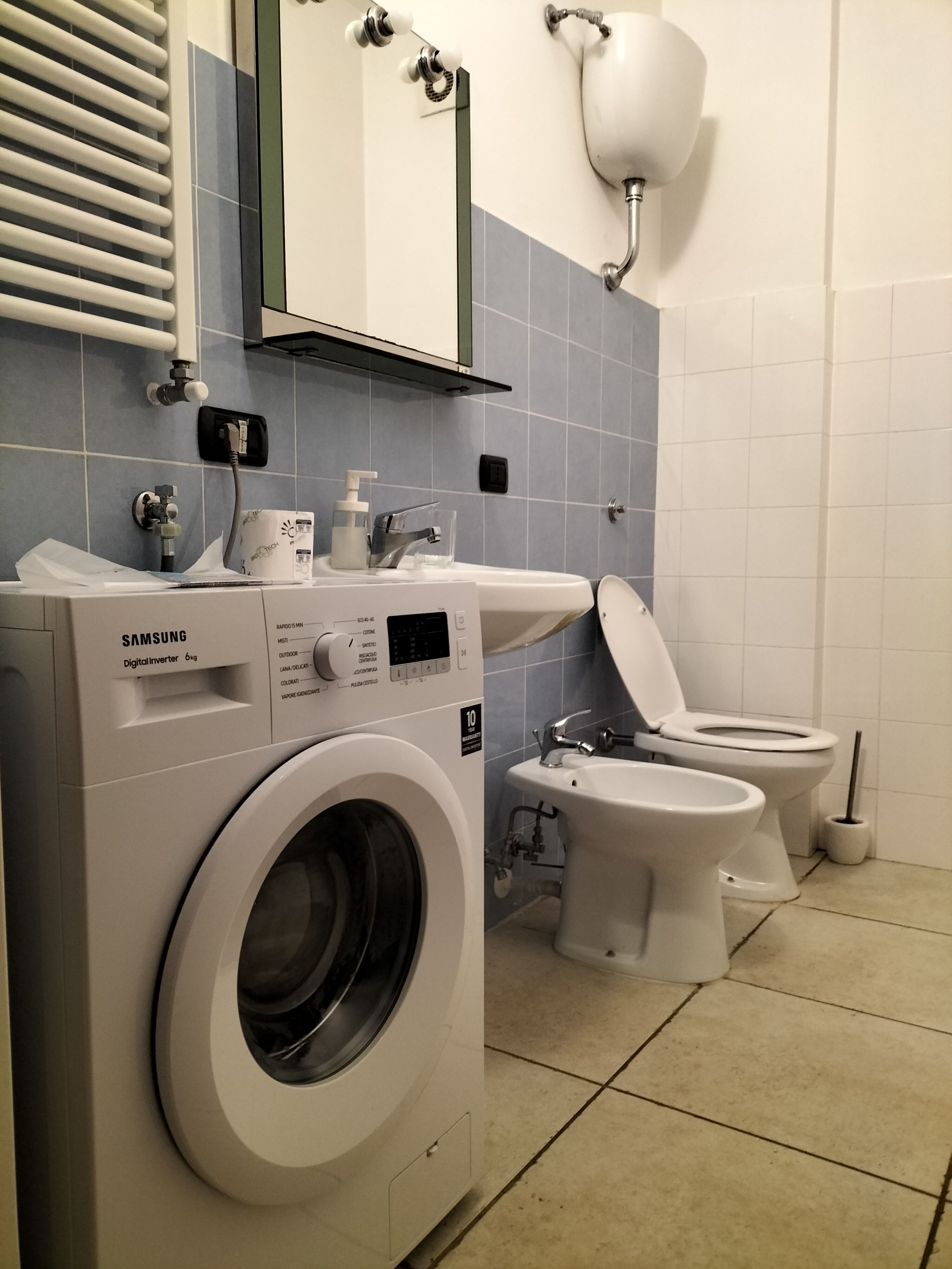A modern bathroom with a washing machine, a sink, and a toilet.