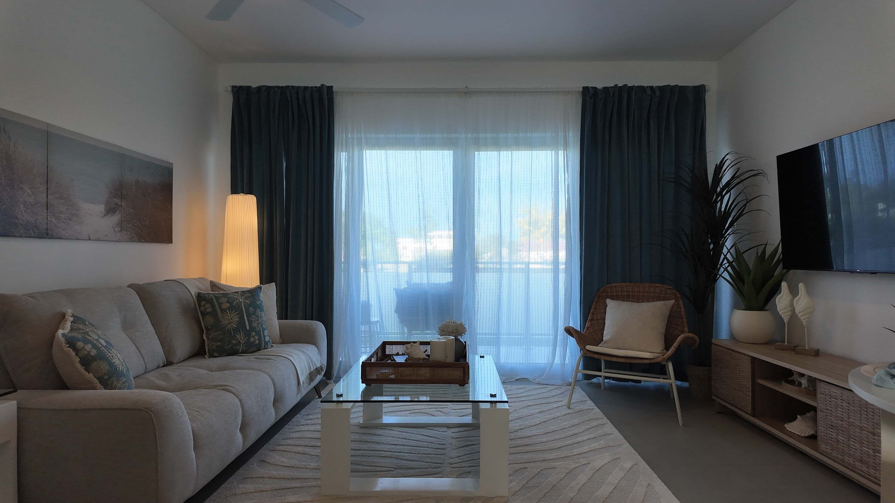 Un salon comprenant un canapé, un fauteuil, une table basse et un téléviseur fixé au mur.