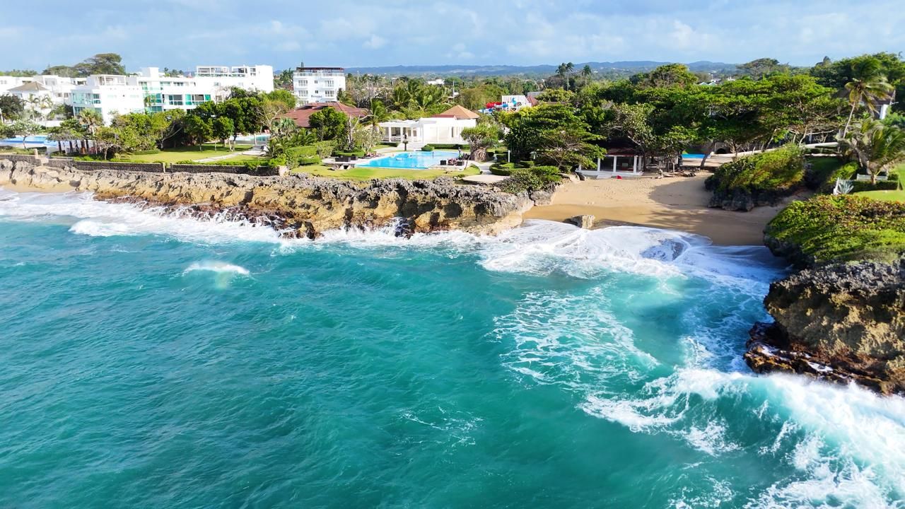 A coastal property with a beach, a swimming pool, and a view of the ocean.