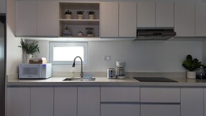 Eine moderne Küche mit Mikrowelle, Toaster, Kaffeemaschine und einem Fenster über der Spüle.