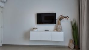 Ein modernes Wohnzimmer mit einem Wandfernseher, einem weißen Konsolentisch und dekorativen Vasen.