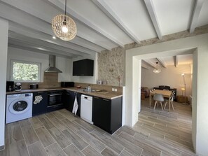 Eine moderne Küche mit integriertem Waschmaschine, Essbereich mit Tisch und Stühlen sowie ein Wohnbereich mit Sofa.