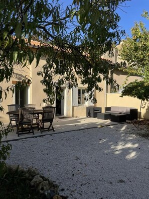 An outdoor patio area with a table and chairs, a sofa, and a small garden. - Le Gîte de l'Abbaye - FONTAINE LE COMTE (FONTAINE LE COMTE)