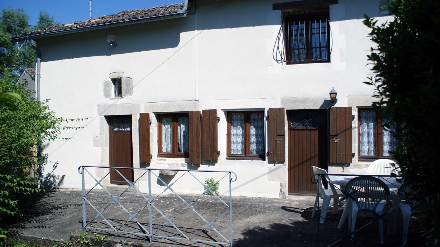 A building with a white facade, wooden shutters, and a gated entrance.
