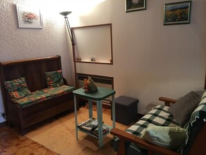 Ein gemütliches Wohnzimmer mit einer Couch, einem kleinen Tisch und einem Bücherregal.