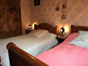 Ein Zimmer mit zwei Betten, einer Wandteppich und Wandlampen.