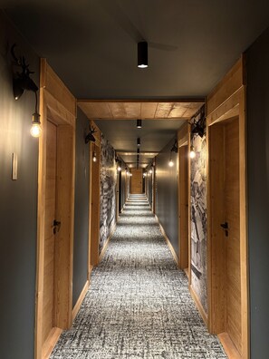 Un couloir aux murs recouverts de lambris, doté d’un tapis à motifs et de luminaires fixés au mur.