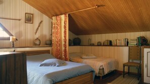 A bedroom with two beds, a wooden ceiling, a bookshelf, and a chair. - La Boulitte - ASNOIS (ASNOIS)