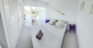 A bedroom with a bed, pillows, a nightstand, a lamp, and a wall-mounted branch. - Beautiful, relaxing apartment with views in Sagaró (Sant Feliu de Guíxols)