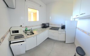 A compact kitchen with white cabinets, a built-in microwave, a sink, and a refrigerator. - Beautiful, relaxing apartment with views in Sagaró (Sant Feliu de Guíxols)
