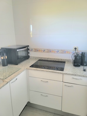 A kitchen with a black toaster oven, a gas stove, white cabinets, and a tiled backsplash. - Beautiful, relaxing apartment with views in Sagaró (Sant Feliu de Guíxols)